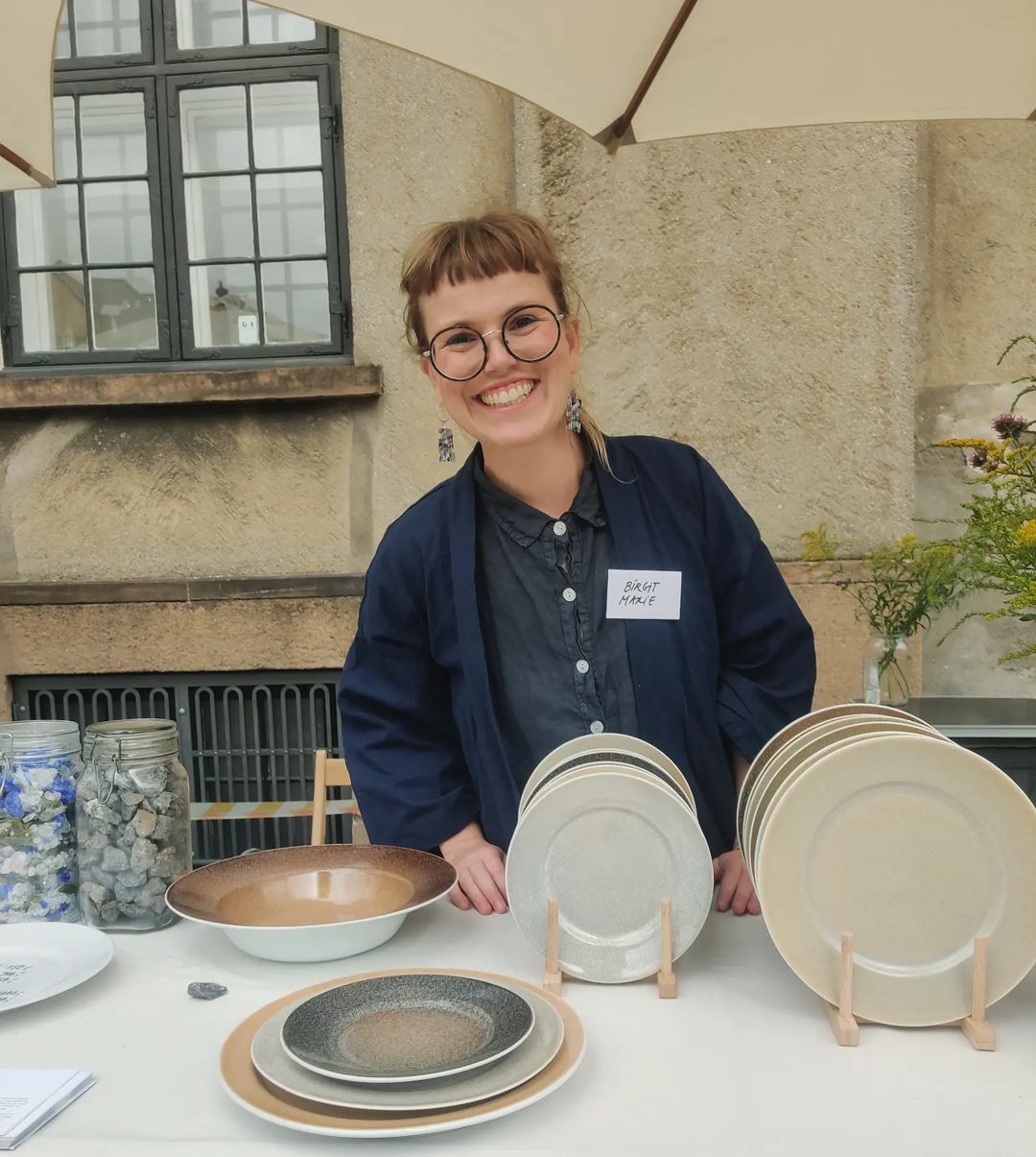 Smilende Birgit Marie stående på marked med Replated tallerkenerne